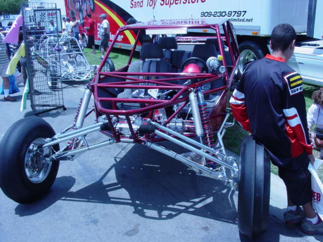 custom dune buggy with red frame and large rear tires, parked outside