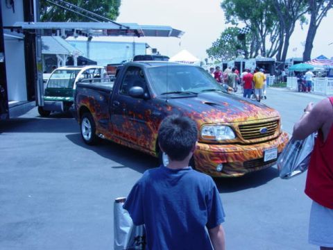 1992 Ford Bronco - A custom Ford F-150 pickup truck with flame graphics is displayed at an outdoor event.