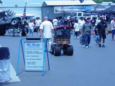 1992 Ford Bronco - An off-road vehicle pulls a cart at an outdoor expo, with a sign for a coffee bar nearby.