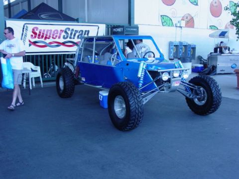 1992 Ford Bronco - A custom blue off-road buggy is displayed at an event, a prominent roll cage and heavy-duty suspension.
