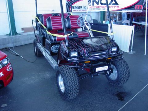 1992 Ford Bronco - A custom golf cart with flame decals and red and black striped seats is on display.