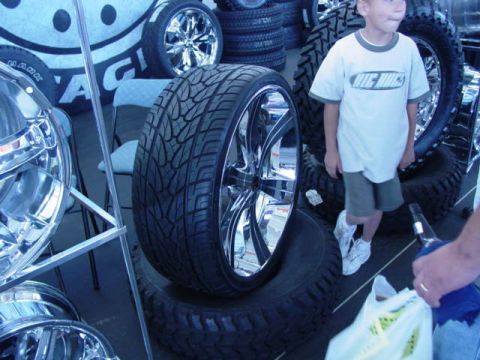 1992 Ford Bronco - A display of custom chrome wheels and tires at an automotive show.