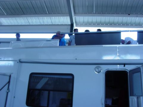 1992 Ford Bronco - People are visible on the roof of a large white vehicle, possibly an RV or trailer.