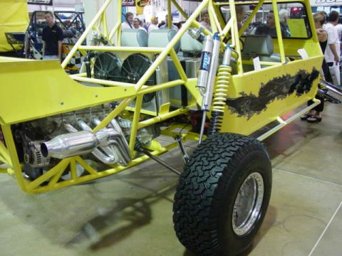 1992 Ford Bronco - A custom-built yellow off-road buggy is displayed indoors, a prominent roll cage and exposed engine components.