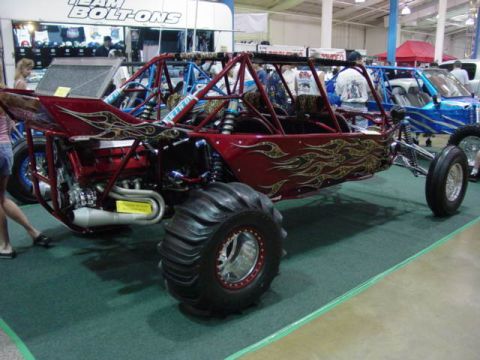 1992 Ford Bronco - A custom red dune buggy with flame graphics is displayed indoors next to another vehicle.