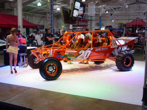 1992 Ford Bronco - Custom dune buggy on display at an indoor event, large off-road tires and a roll cage.