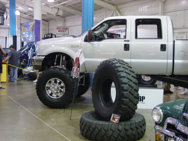Lifted silver pickup truck with massive off-road tires on display