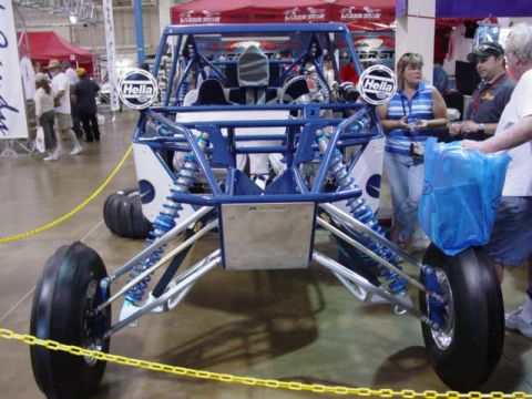 1992 Ford Bronco - This custom off-road buggy features a prominent blue roll cage and suspension system, displayed indoors.