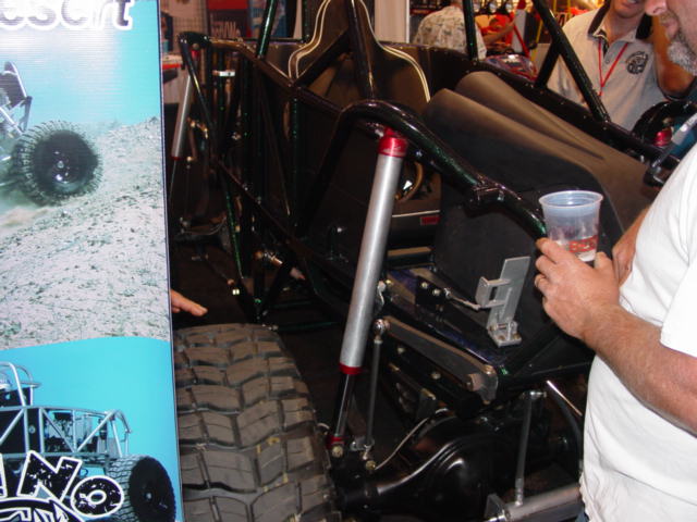 Black off-road buggy with large tires and roll cage, viewed from the side