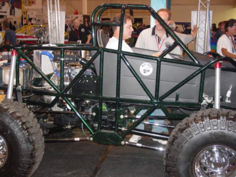 1992 Ford Bronco - Custom buggy with roll cage and large tires on display indoors.