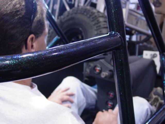 guy in white shirt in roll cage of off-road vehicle, looking at dashboard gauges