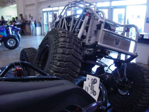 1992 Ford Bronco - An off-road buggy with a roll cage and large tires is displayed indoors, with a blue ATV visible in the background.