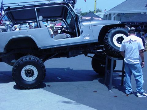 1992 Ford Bronco - A modified Jeep Wrangler is showcased at an off-road show, highlighting its custom suspension and oversized wheels.