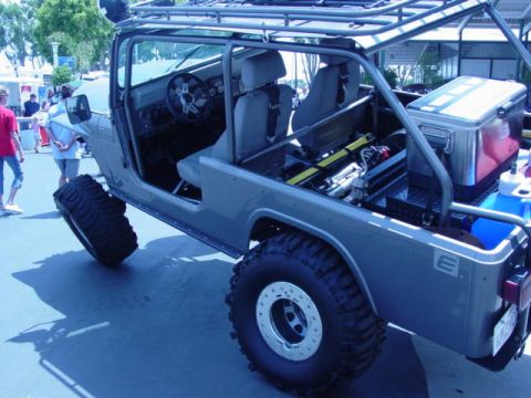 1992 Ford Bronco - This modified Jeep CJ-7 features an extended roll cage and a roof rack, with large off-road tires visible.