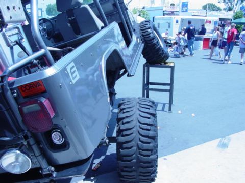 1992 Ford Bronco - A heavily modified Jeep Wrangler is displayed with one tire elevated on a stand at an outdoor event.