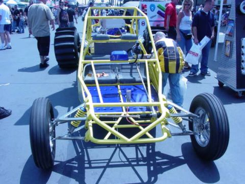1992 Ford Bronco - A yellow dune buggy with blue seats is displayed at an off-road show.