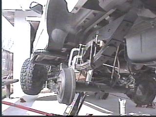 1993 Ford Bronco - Undercarriage of a vehicle, likely undergoing maintenance or repair. SuperMotors logo is visible.