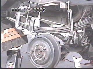 1993 Ford Bronco - Close-up of a vehicle's rear suspension system, showing leaf springs and brake components.