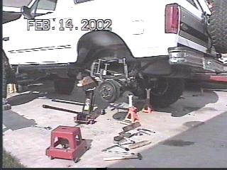 1993 Ford Bronco - White Ford Bronco rear end undergoing mechanical work with suspension components removed.