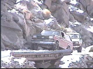 1993 Ford Bronco - Two SUVs navigate a challenging, snow-dusted rocky terrain.