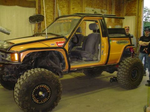 1993 Ford Bronco - Customized Toyota pickup truck with extensive off-road modifications, including a roll cage and oversized tires.