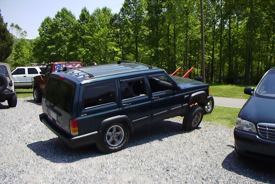Dark green Jeep Cherokee XJ parked on gravel, side view