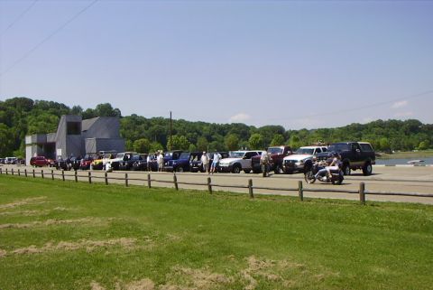1995 Ford Bronco - A group of vehicles are parked in a lot on a sunny day, with a motorcycle in front.