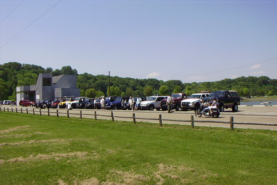 Line of SUVs and trucks parked near a building with a motorcycle in the foreground