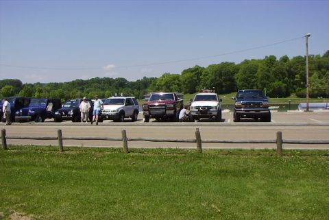 1995 Ford Bronco - Several vehicles are parked in a lot on a sunny day.