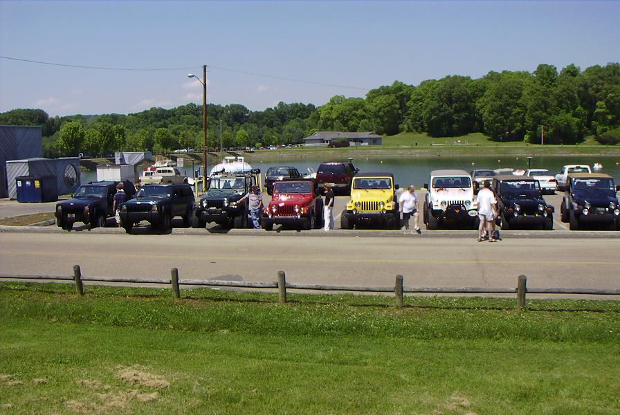Several Jeeps parked in a row near a body of water
