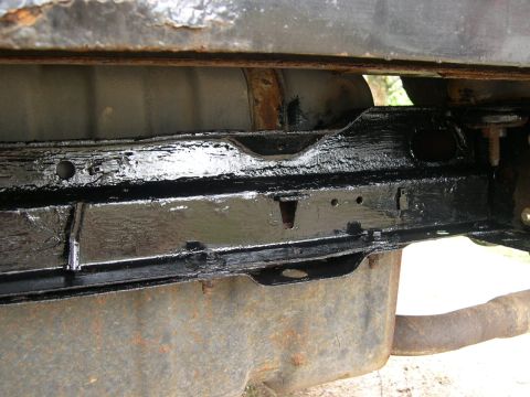 1994 Ford Bronco - The underside of a vehicle reveals its frame, fuel tank, and exhaust system, with some components recently painted.