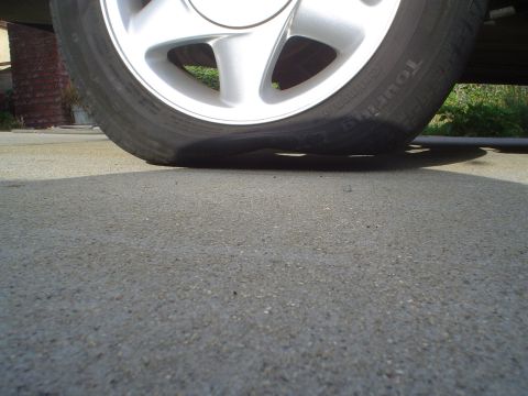 1993 Ford Taurus - A car's tire is completely flat, resting on the pavement.