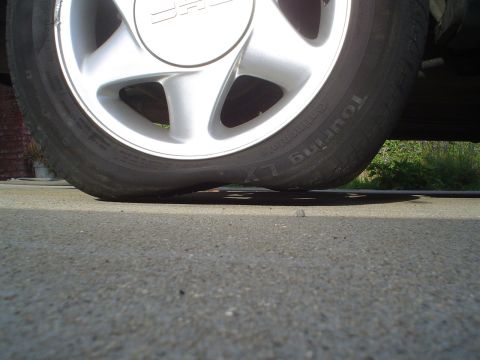 1993 Ford Taurus - A vehicle's tire is flat against the pavement.