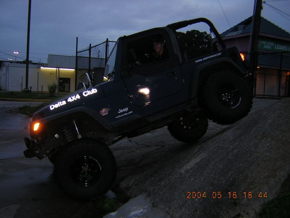 Dark blue Jeep Wrangler on an incline, with "Delta 4X4 Club" text on the fender