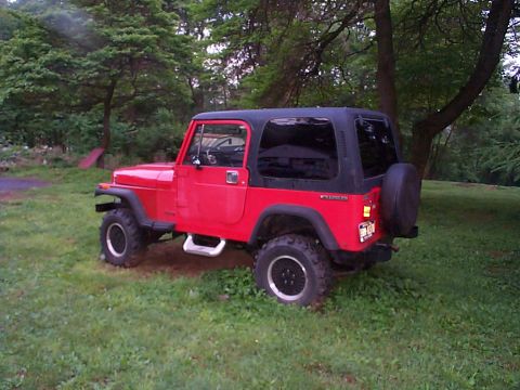 1989 Jeep YJ - This red 1989 Jeep YJ is shown from a three-quarter front view, parked outdoors on a grassy lawn.