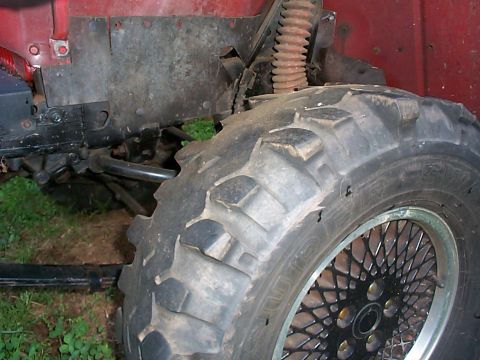 1989 Jeep YJ - Close-up of the front tire and suspension of a red Jeep YJ.