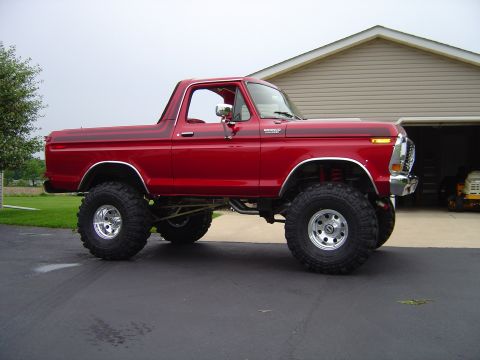 1978 Ford Bronco - This lifted red Ford Bronco sits in a driveway with a garage behind it.