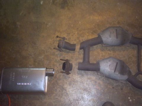 1991 Ford LTD Crown Victoria - Disassembled exhaust system components laid out on a textured surface.