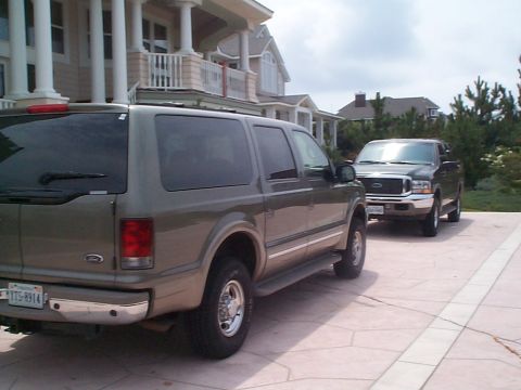 2001 Ford Excursion - Two Ford vehicles, a 2001 Excursion and an F-250 Super Duty, are parked in front of a large house.