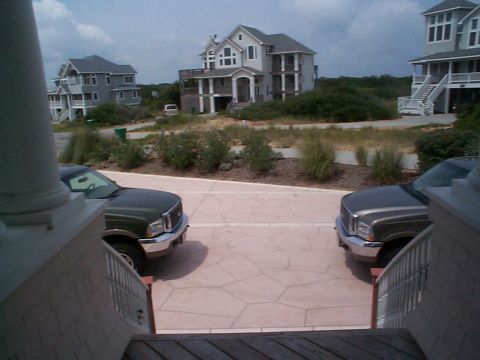 2001 Ford Excursion - Two Ford Super Duty trucks are parked on a paved driveway in front of several beach houses.