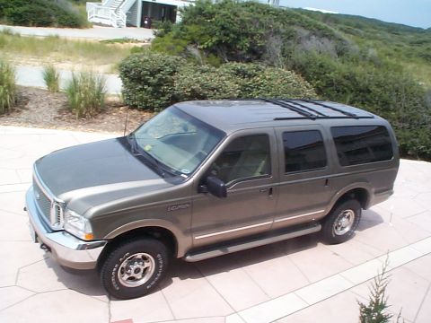 2001 Ford Excursion - A brown Ford Excursion is parked on a tiled patio with a house and vegetation in the background.