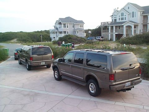 2004 Ford Excursion - Two Ford Excursions are parked in front of large beach houses, suggesting a vacation destination.