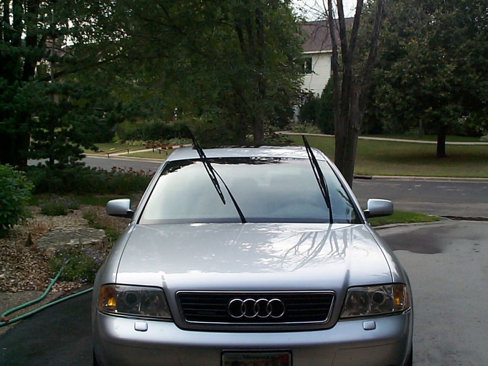 Front view of silver Audi sedan with wipers raised, parked in driveway