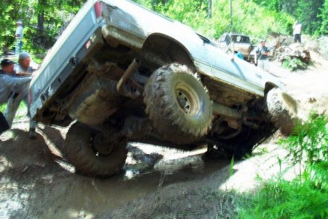 1988 Ford Bronco - A 1988 Ford Bronco is stuck in the mud during an off-road event, with onlookers attempting to free it.