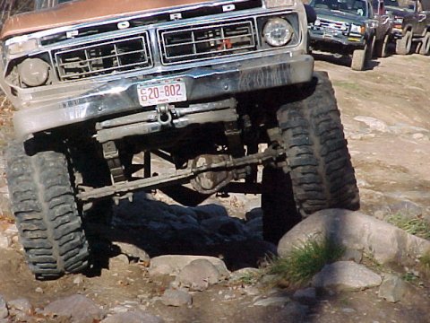 1976 Ford F-250 - A line of trucks, including a brown Ford, navigates a rocky off-road course.