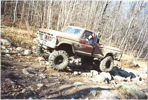 1976 Ford F-250 - This pickup truck is navigating a challenging off-road course with large rocks and uneven terrain.