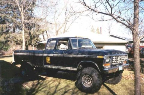 1978 Ford F-250 - This lifted 1978 Ford F-250 pickup truck is parked in a grassy yard with trees and a house in the background.