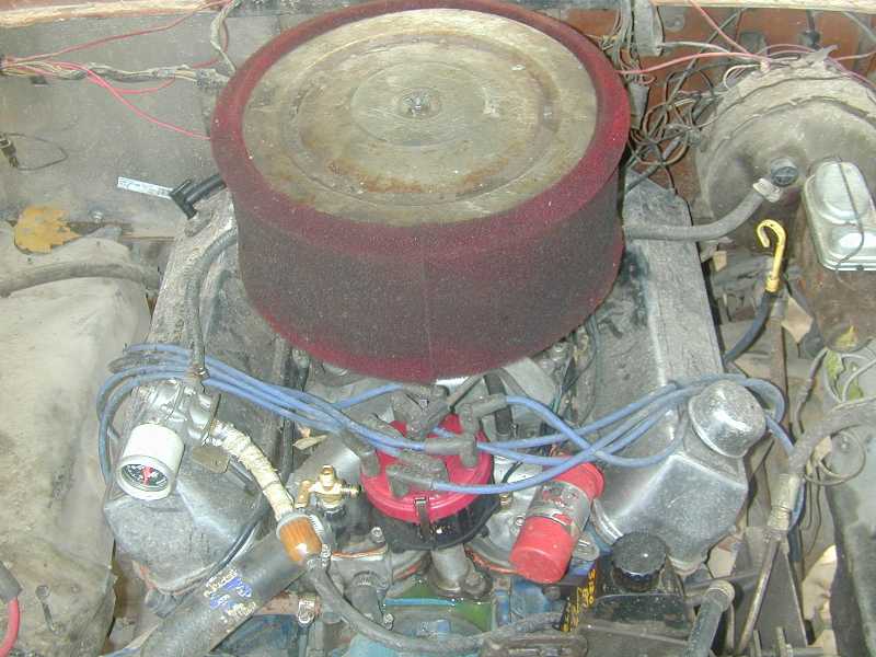 Engine bay with round air cleaner, maroon foam wrap, blue plug wires and distributor