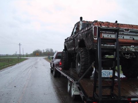 2000 Ford F-350 - Mud-caked lifted Ford truck being transported on a trailer, with a visible license plate.
