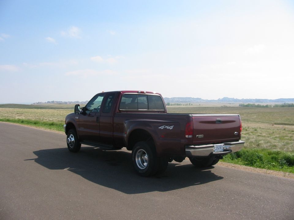 Maroon Ford F-350 4x4 dually pickup viewed from rear left on a rural road